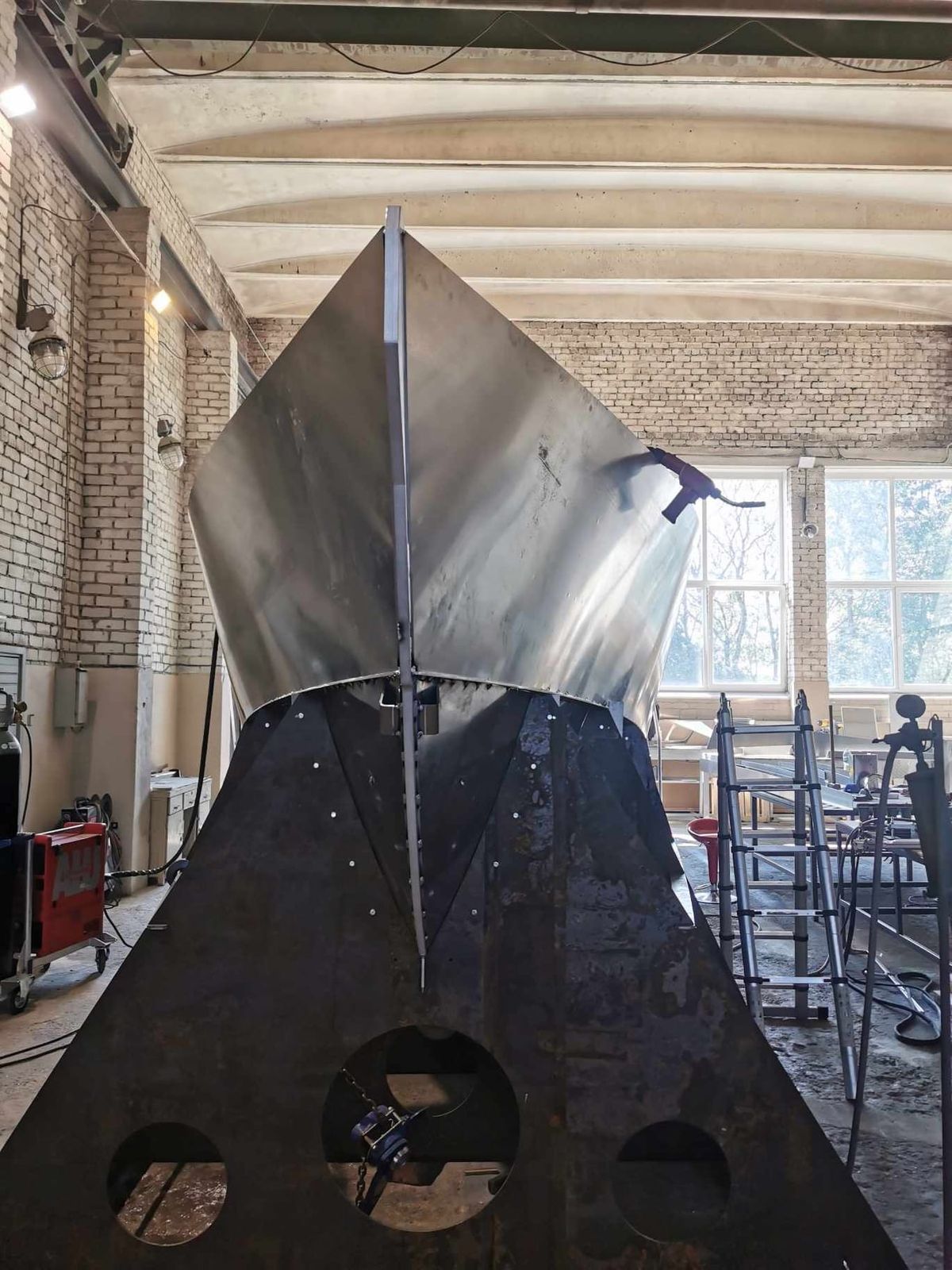 The bow of the AO12 hull under construction, aluminium plating tacked up on the jig in a workshop