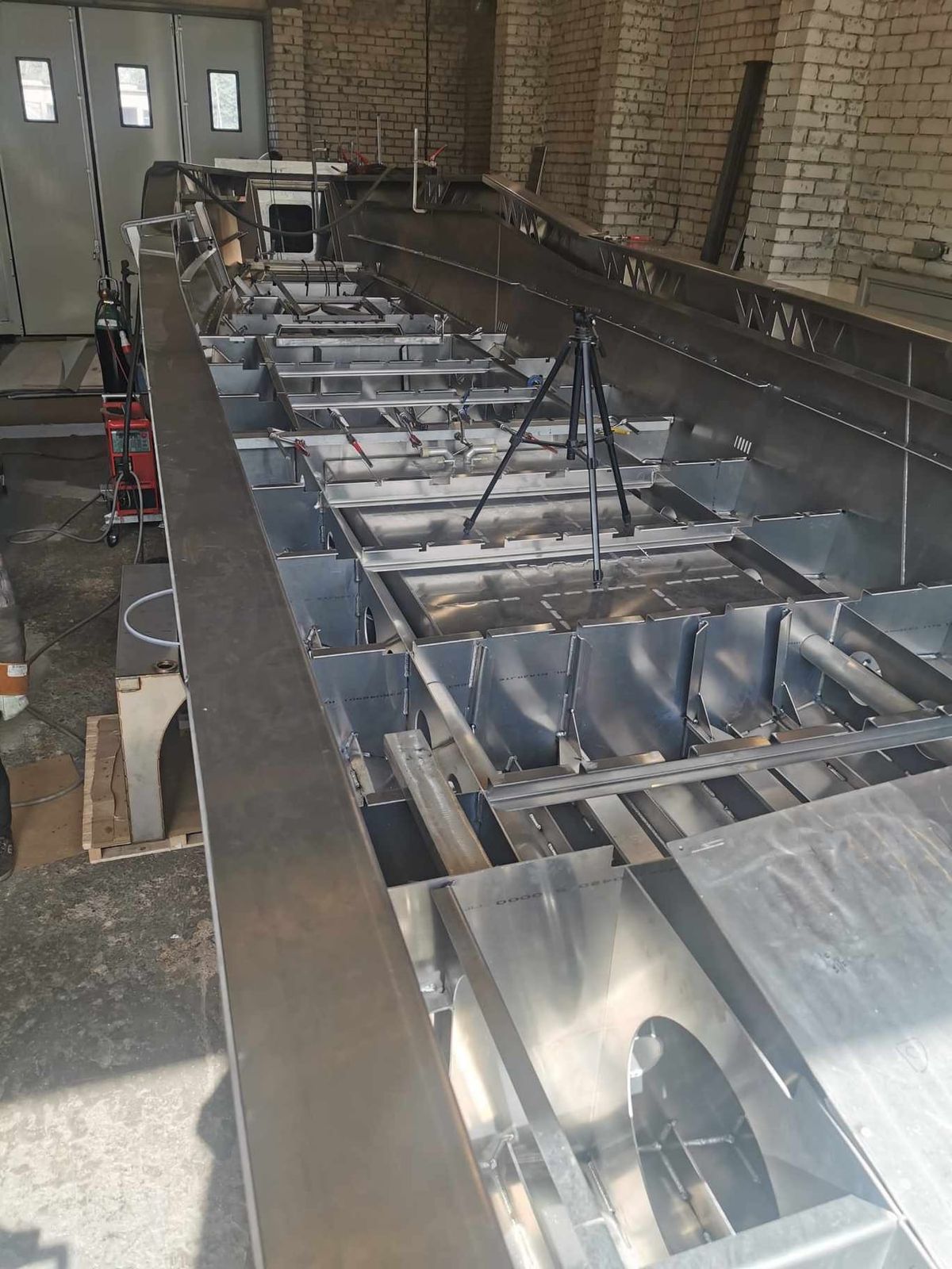 Looking down the length of the AO12 hull under construction, showing the welded frames and the compartments built into the bottom of the hull