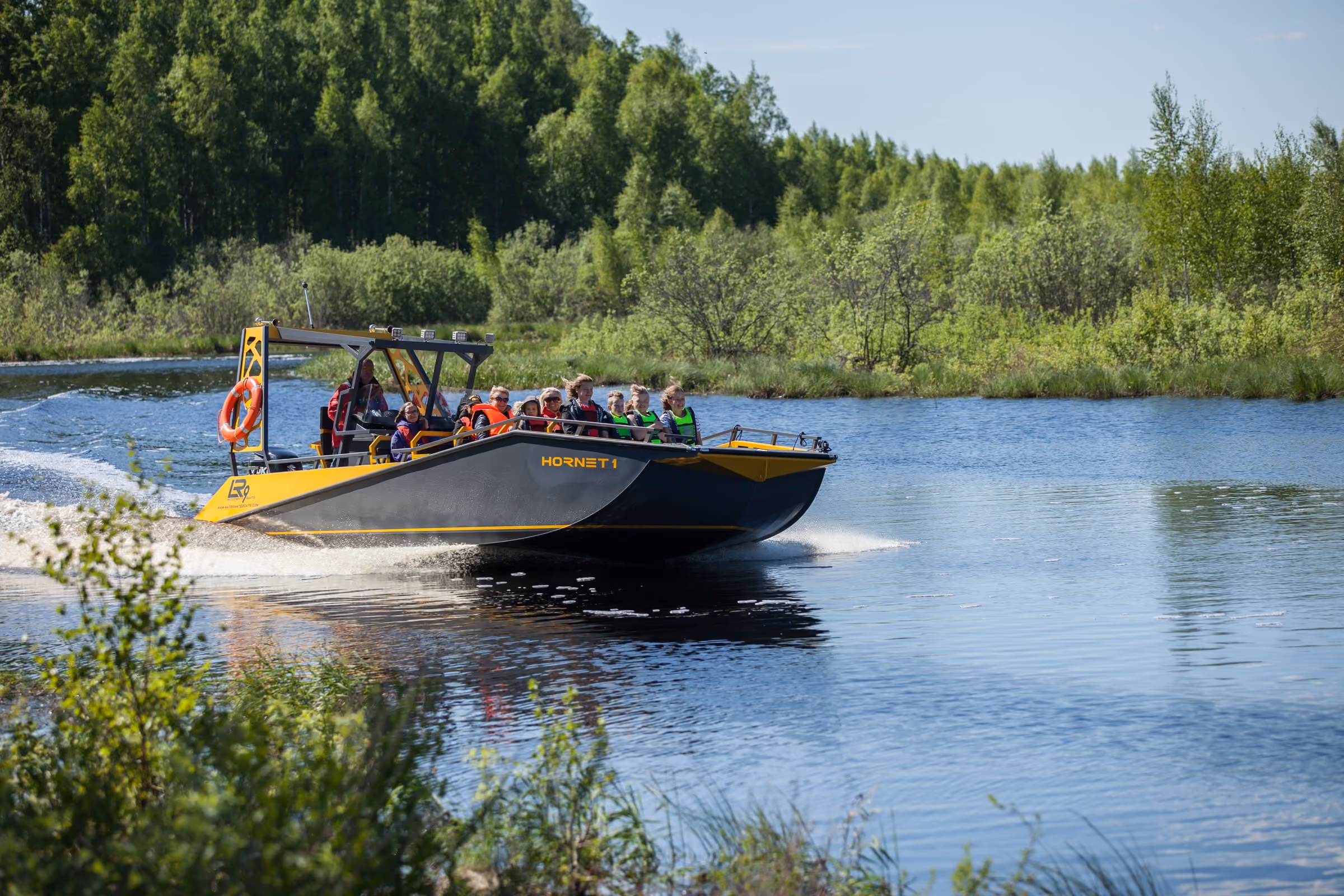 LR9 Safari running at speed down a narrow wooded river, passengers in life jackets on the forward benches